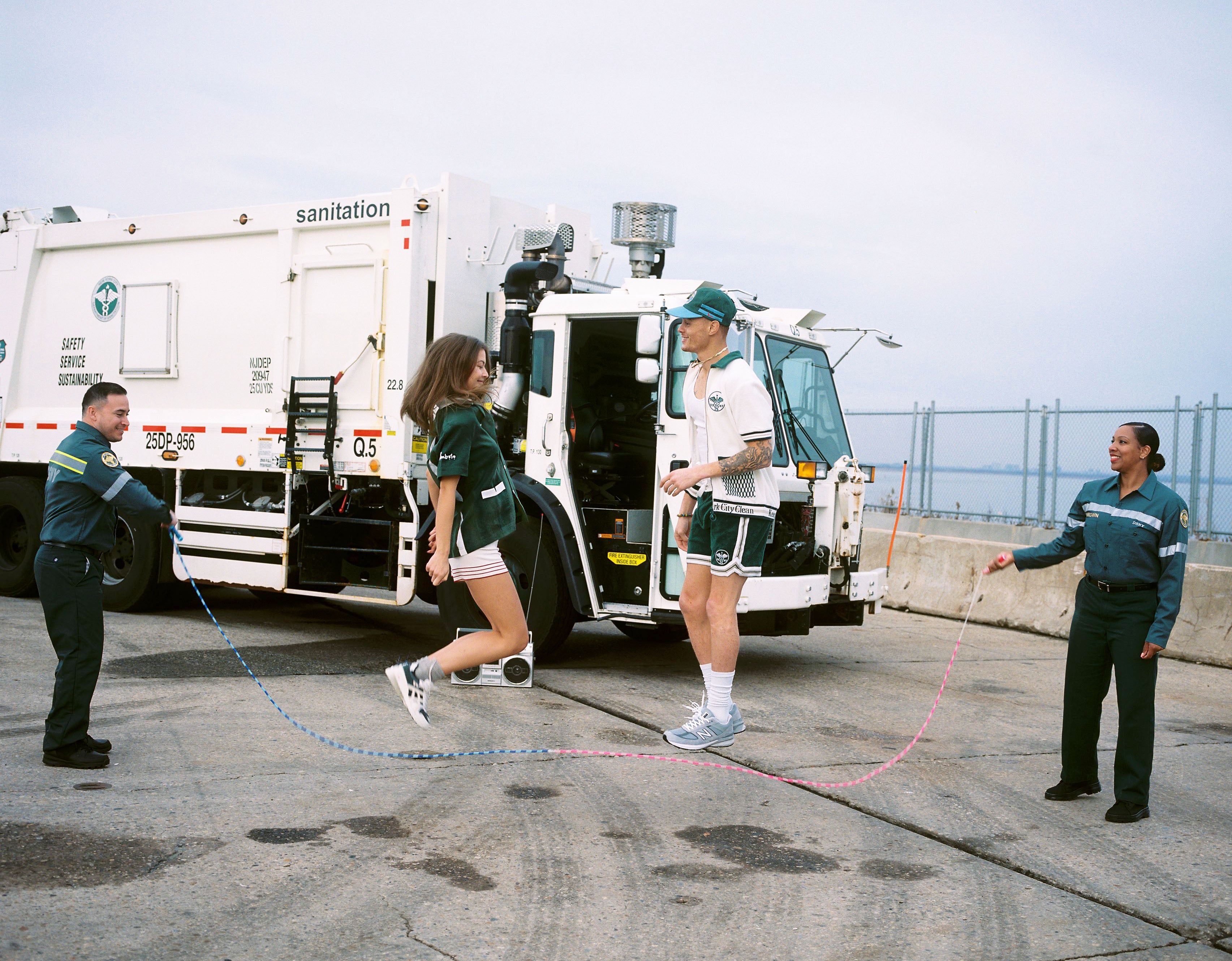 Male and female models in the DSNY collab jump roping with sanitation workers holding either end of the rope