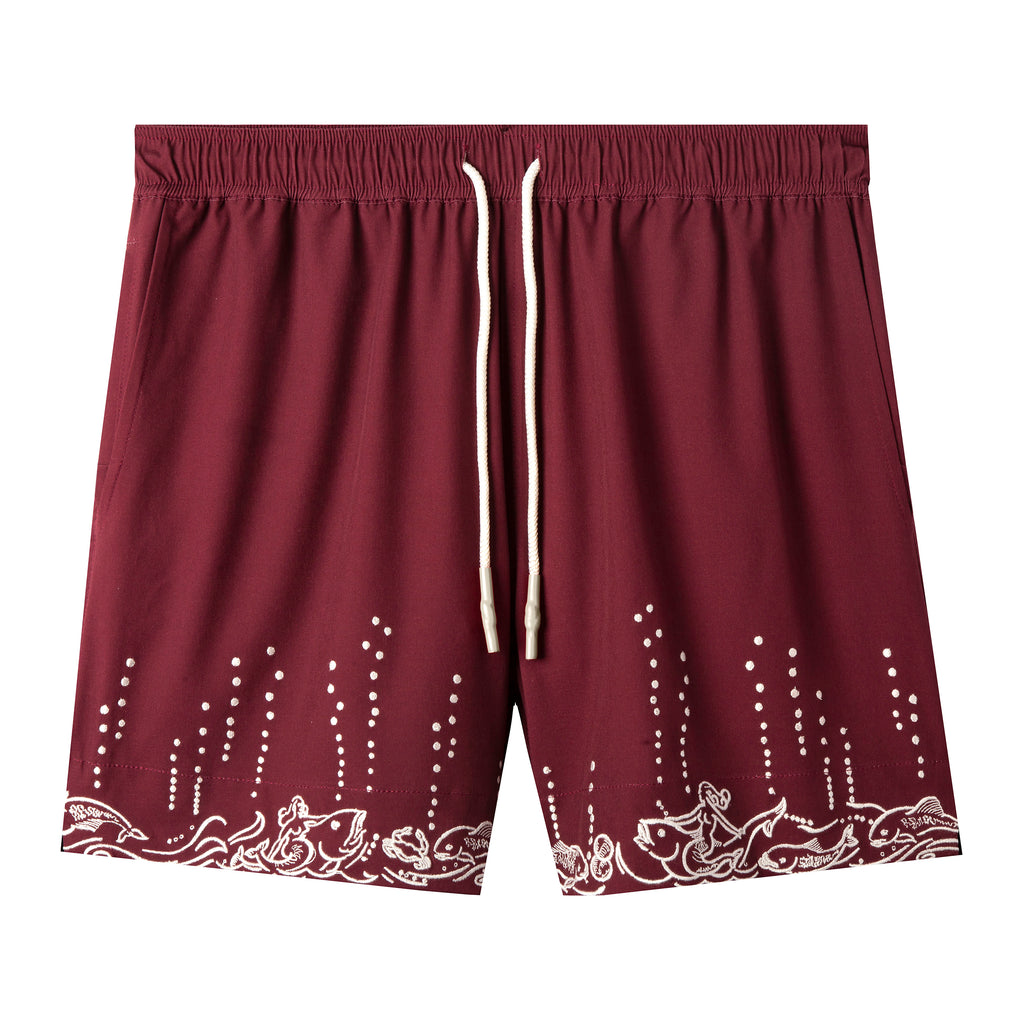 Maroon swim trunks with embroidered fish and mermaids at the leg openings with white bubbles climbing up the legs