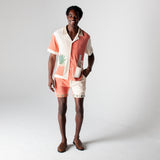 Full body image of male model wearing the Gusanito cabana set, with an empty tequila bottle in the outer right pocket