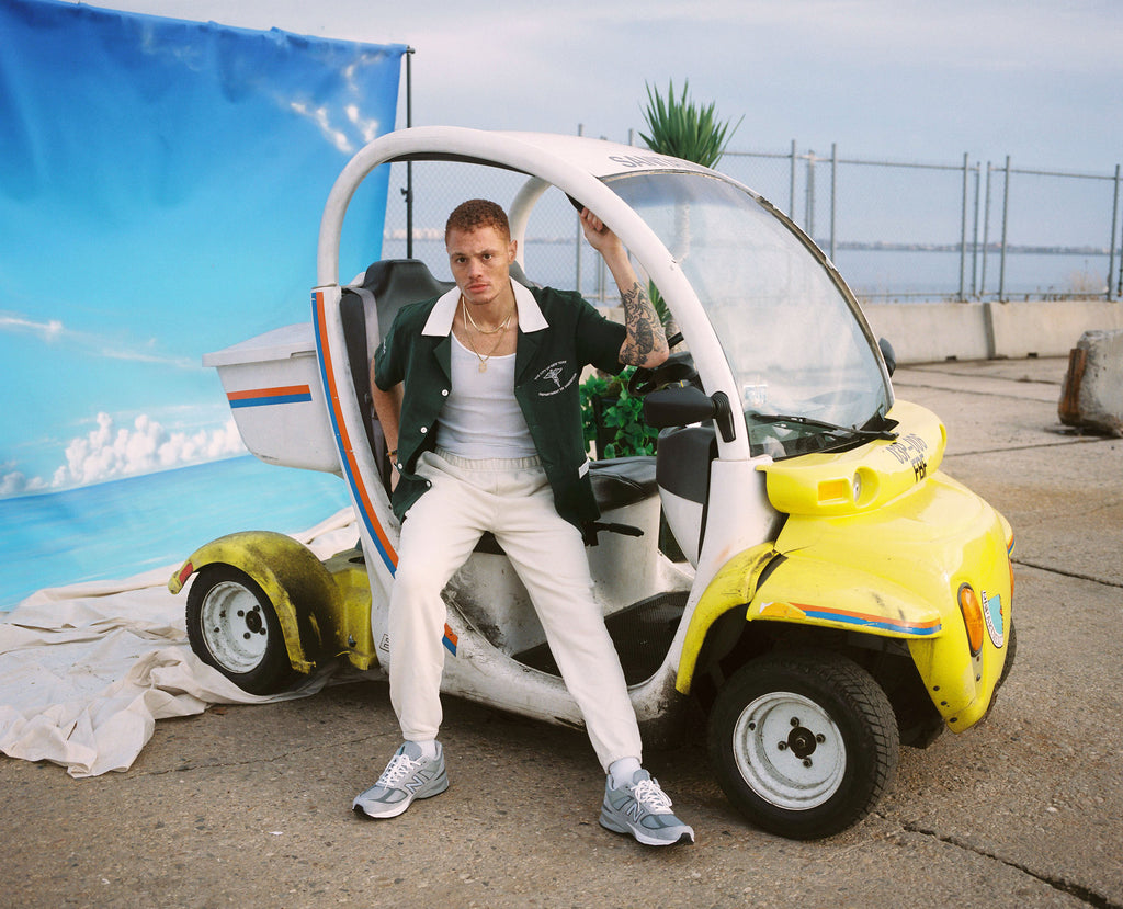 Male model sitting in sanitation car in DSNY shirt
