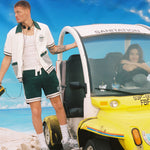 Man holds onto outside of DSNY car as woman stares at camera from driver's seat