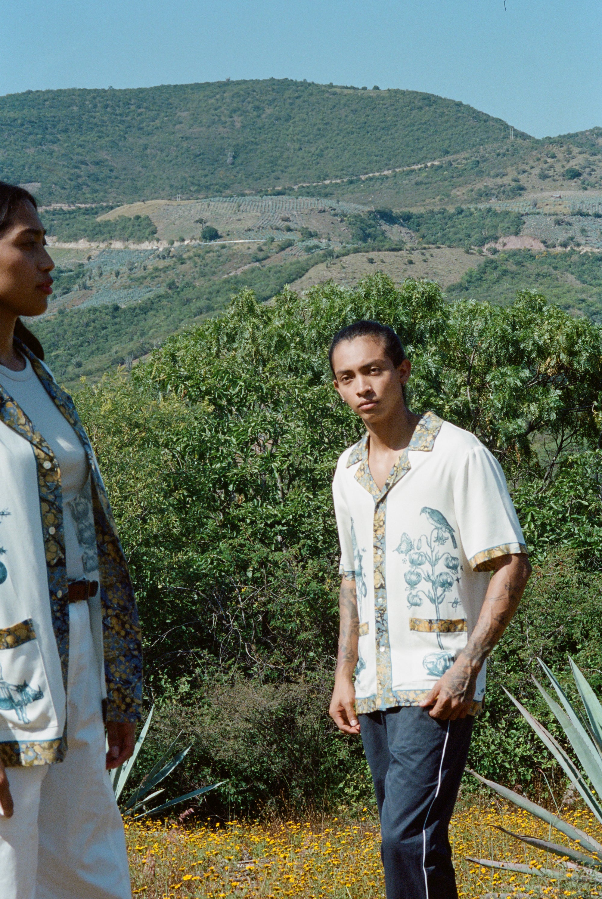 Man standing on hilltop wearing Alexis Zambrano shirt